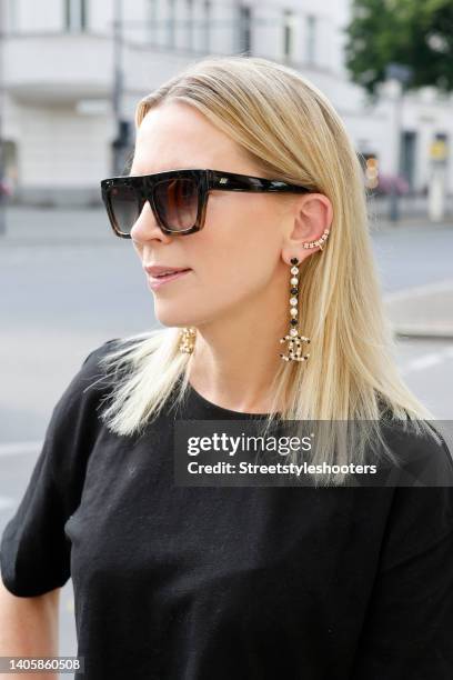 Tamara von Nayhauss wearing a black cropped t-shirt by Zara, black and gold drop logo earrings with pearls and crystals by Chanel, a gold ear cuff...