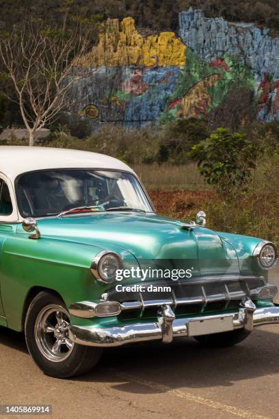 old american car with colourful mural wall from vinales, cuba - prehistoria stock pictures, royalty-free photos & images