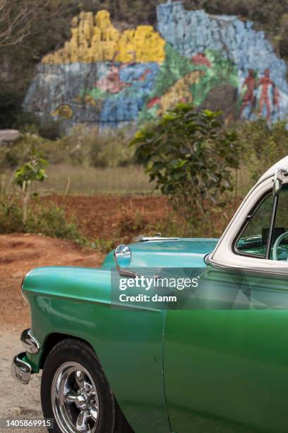 old american car with colourful mural wall from vinales, cuba - prehistoria stock pictures, royalty-free photos & images