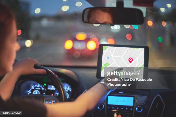 woman sitting in car and using navigation system - navigational equipment stockfoto's en -beelden
