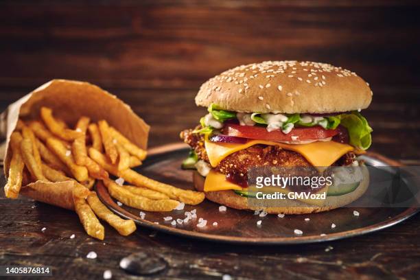 crispy chicken burger with cheese, tomato, onions and green salad - kipburger stockfoto's en -beelden