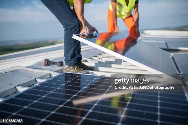zwei ingenieure, die sonnenkollektoren auf dem dach installieren. - installieren stock-fotos und bilder