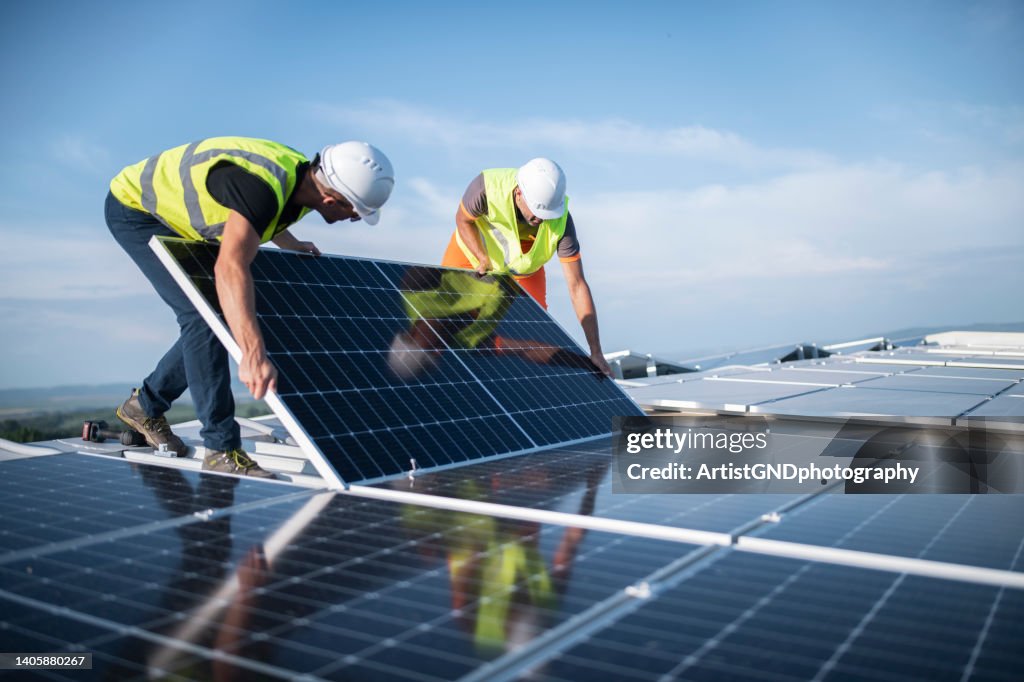 Deux ingénieurs installant des panneaux solaires sur le toit.