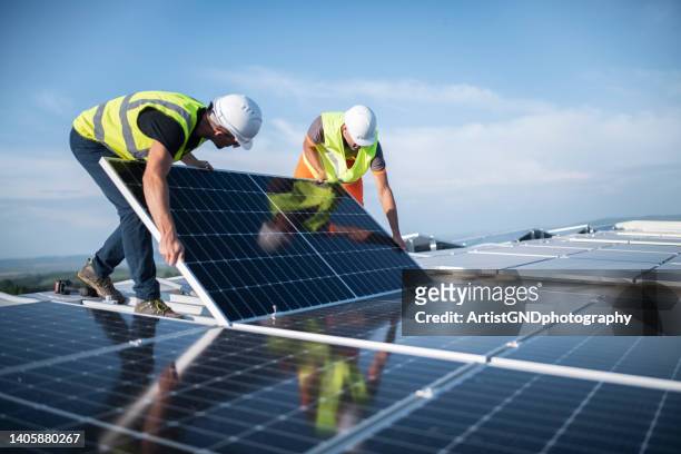 two engineers installing solar panels on roof. - industry imagens e fotografias de stock