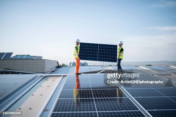 arbeiter, die eine photovoltaikanlage auf einem lagerdach installieren. - solar system stock-fotos und bilder