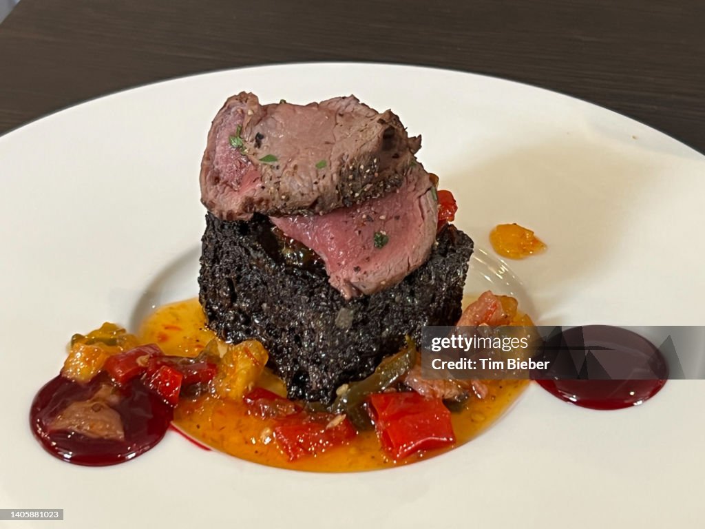 Sliced filet beef venison, cooked medium rare, over black pudding haggis with vegetable sauce