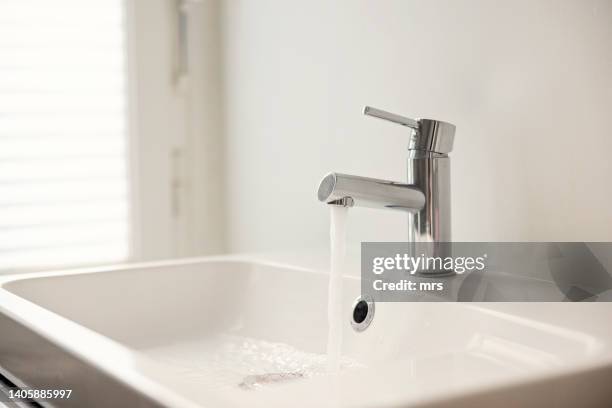 water pouring from sink faucet - bathroom ストックフォトと画像