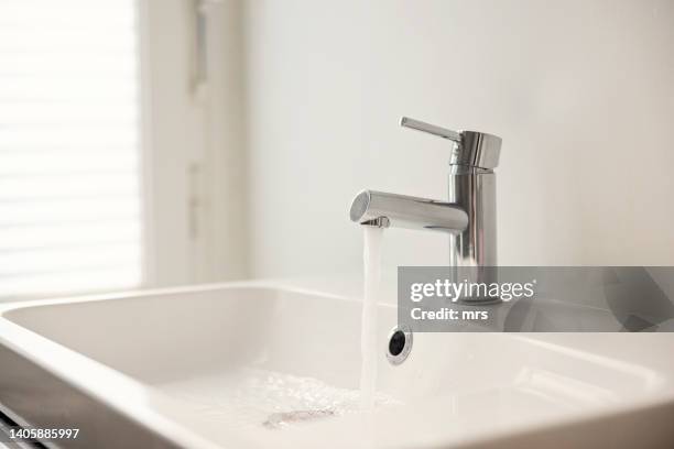 water pouring from sink faucet - fontein stockfoto's en -beelden