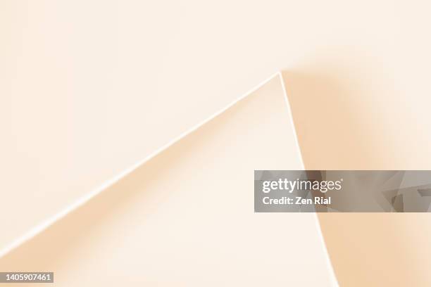 beige color paper twice folded forms acute angle - beigefarbiger hintergrund stock-fotos und bilder