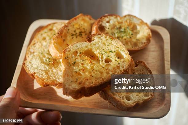 close-up view of the herb garlic bread on the wooden tray - garlic bread stock pictures, royalty-free photos & images