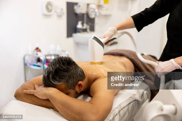 homem recebendo um tratamento de depilação nas costas em um spa - medical laser - fotografias e filmes do acervo