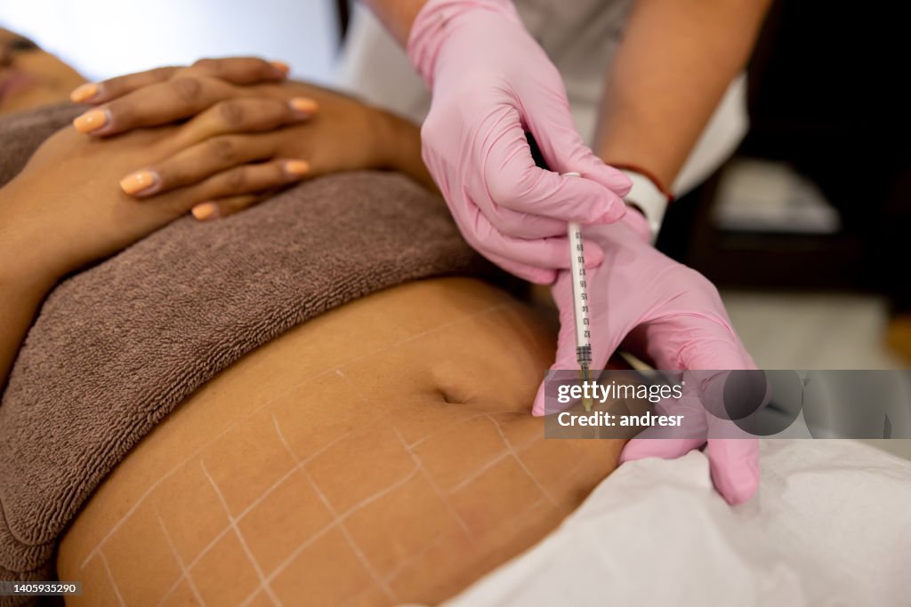 Close-up on a woman getting fat burning injections in her abdomen