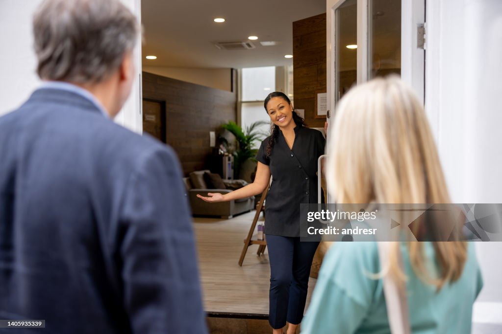 Business owner at a spa opening the door to a couple of customers