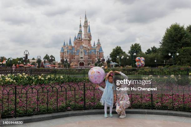 People pose in front of the Enchanted Storybook Castle at Shanghai Disneyland on June 30, 2022 in Shanghai, China. Shanghai's Disneyland theme park...
