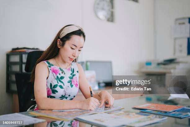 asian chinese female school teaching marking student works on her desk in her workplace - grading stock pictures, royalty-free photos & images