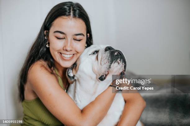 latina young woman petting dog at home in domestic environmnet - home sweet home dog stock pictures, royalty-free photos & images