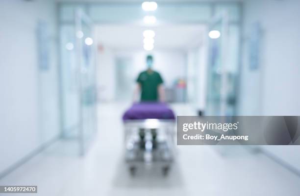 blurred image of an unidentified healthcare worker while pulling an emergency stretcher without patient at hospital corridor. - er stock pictures, royalty-free photos & images