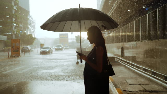 Businesswoman feeling sad during rain while holding umbrella