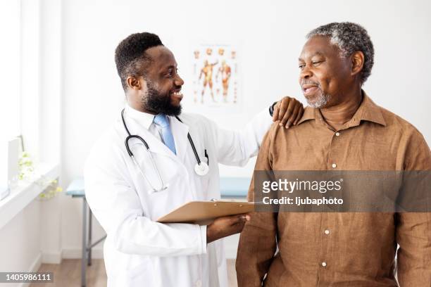 male doctor checking senior male patient and smiling - african american patient stock pictures, royalty-free photos & images