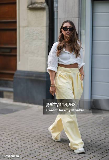 Kira Bejaoui seen wearing black Celine sunglasses, gold pendant necklace, a white blouse shirt, a creme beige leather bag from Weat, a yellow...