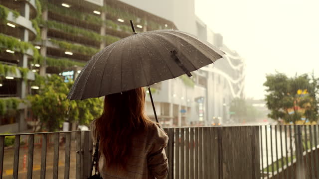 Businesswoman feeling sad during rain while holding umbrella