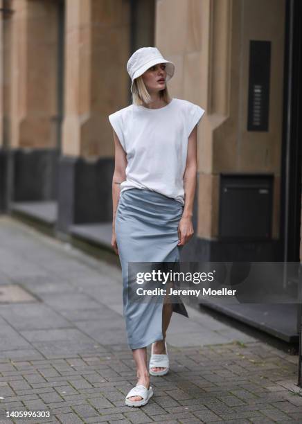 Vanessa Tamkan seen wearing a white bucket hat, a white t-shirt, a grey midi skirt and white sandals from Prada on June 25, 2022 in Cologne, Germany.