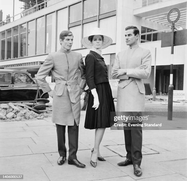 Three fashion models, one female between two males, each wearing Hardy Amies' designs, outside Amies' fashion show held at the London Hilton Hotel on...