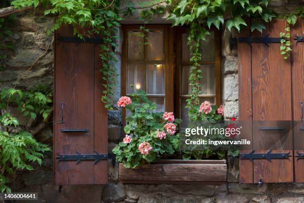 window with flowers and wooden shutters. france - haute savoie stock-fotos und bilder
