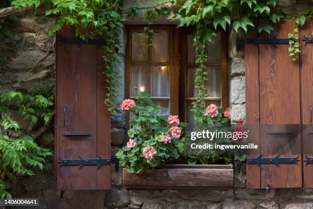 window with flowers and wooden shutters. france - haute savoie - fotografias e filmes do acervo