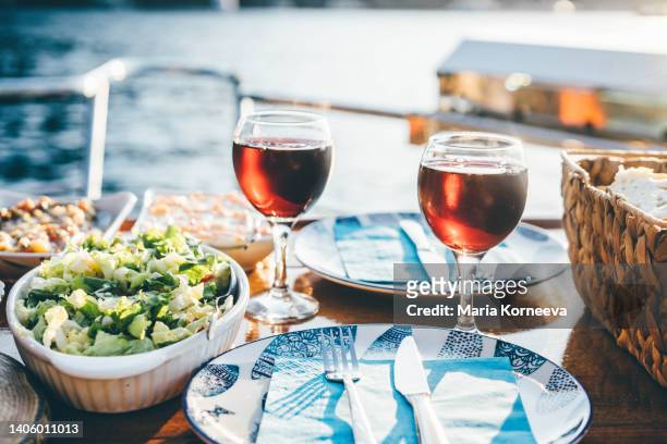 outdoor dinner setting with red wine on the yacht at  sunset. - luxury cruise relaxing stock pictures, royalty-free photos & images
