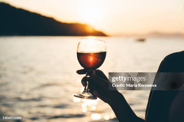 woman drinking wine while enjoys sunset on the sailboat. - sailboat silhouette stock pictures, royalty-free photos & images