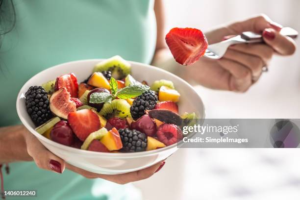 a woman breakfasts a fruit salad high in vitamins and fiber. - macedonia foto e immagini stock