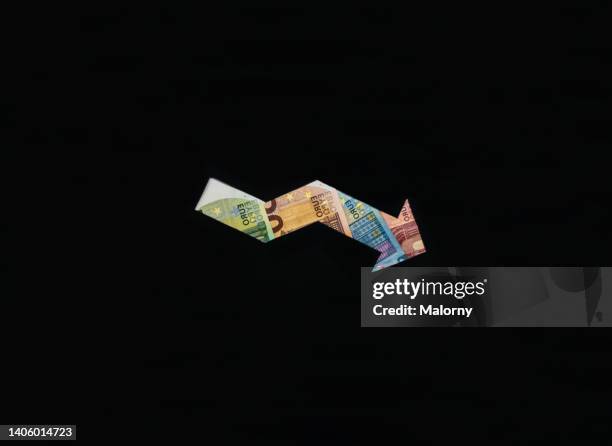 descending arrow made out of euro banknotes. symbolizing inflation, deflation, economic growth or wages. - inflation euro stock-fotos und bilder