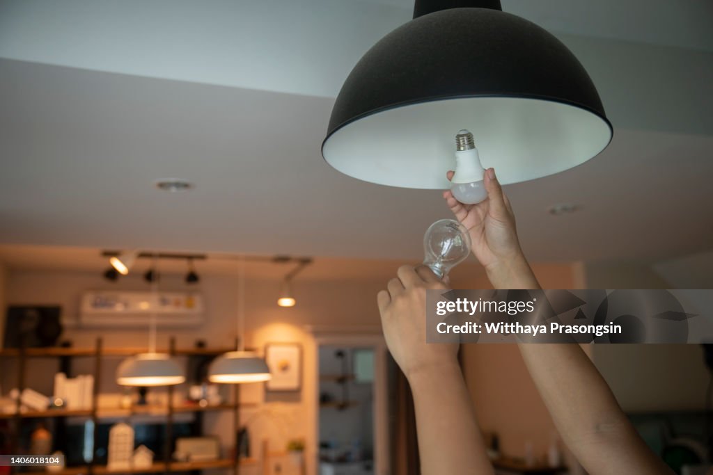 Man changing compact-fluorescent (CFL) bulbs with new LED light bulb.