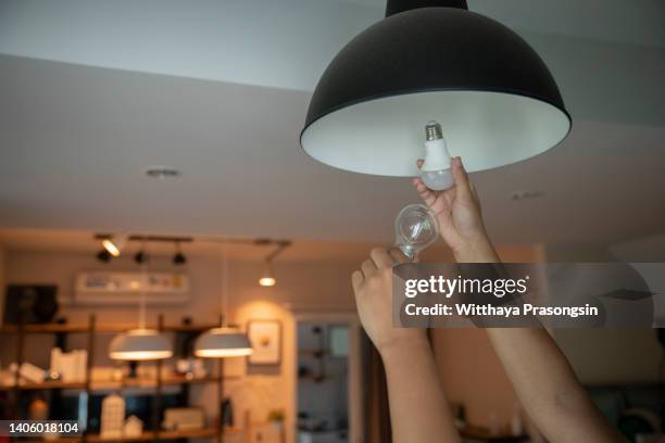 man changing compact-fluorescent (cfl) bulbs with new led light bulb. - lampada elettrica foto e immagini stock