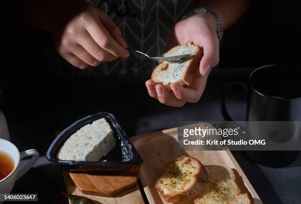 spreading the blue cheese on the garlic bread - garlic bread stock pictures, royalty-free photos & images