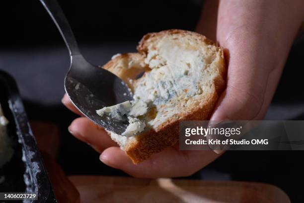 spreading the blue cheese on the garlic bread - gorgonzola stock pictures, royalty-free photos & images