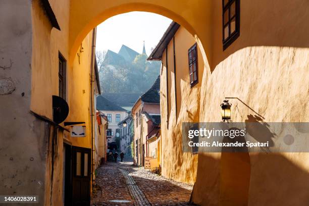 church on the hill seen through the arch in sighisoara village, transylvania, romania - romania traditional stock pictures, royalty-free photos & images