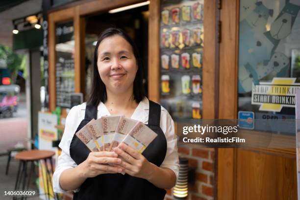 young business owner holding money - thai baht notes stock pictures, royalty-free photos & images