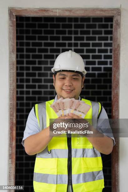 young blue collar worker holding money - film benefit stock pictures, royalty-free photos & images