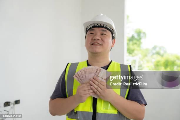 young blue collar worker holding money - film benefit stock pictures, royalty-free photos & images