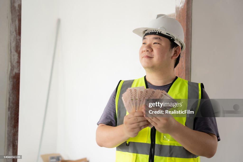 Young Blue Collar worker Holding Money