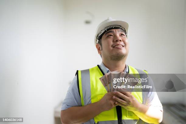 young blue collar worker holding money - film benefit stock pictures, royalty-free photos & images