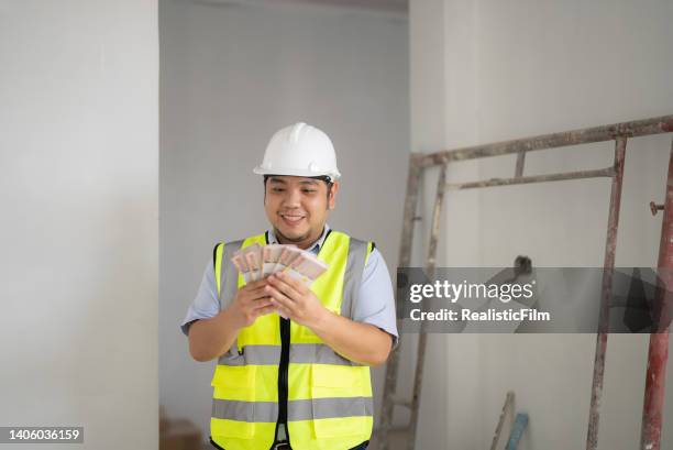 young blue collar worker holding money - film benefit stock pictures, royalty-free photos & images