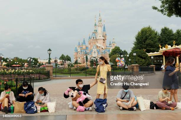 People rest infront of the Enchanted Storybook Castle at Shanghai Disneyland on June 30, 2022 in Shanghai, China.