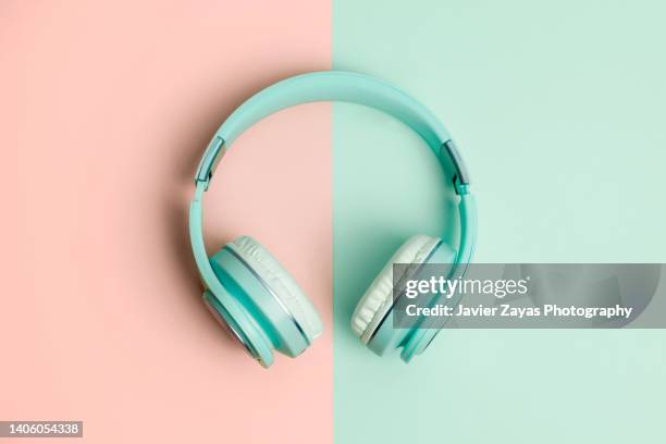 green headphones on a green and salmon background - earbud stock pictures, royalty-free photos & images