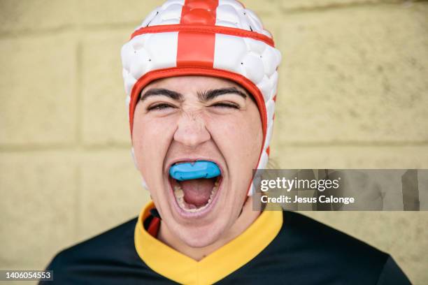 portrait of a woman, rugby player, dressed in rugby clothes and rugby head gear. looking at the camera, with an expression of screaming, and madness. rugby, female sport, contact sports concept. - rugby esporte stock pictures, royalty-free photos & images