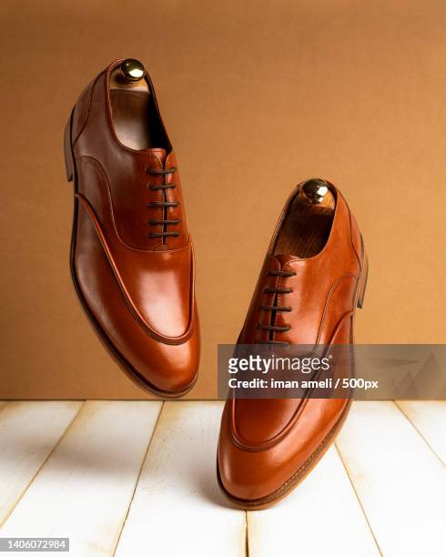 close-up of brown leather shoes on brown table - calzature di pelle foto e immagini stock