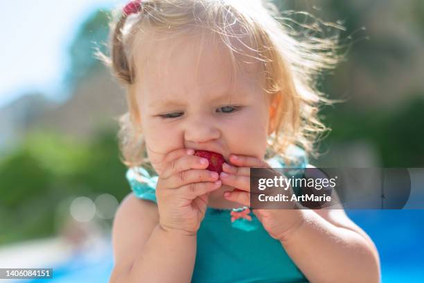 baby girl tastin strawberry near a pool on summer vacations - food allergy stock pictures, royalty-free photos & images
