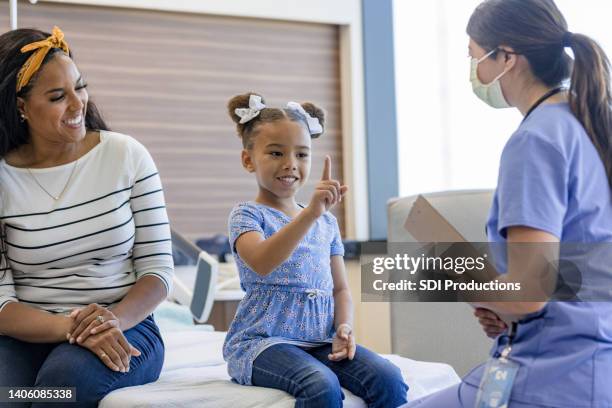 young female patient smiles proudly while listening to the doctor - number 1 mom stock pictures, royalty-free photos & images